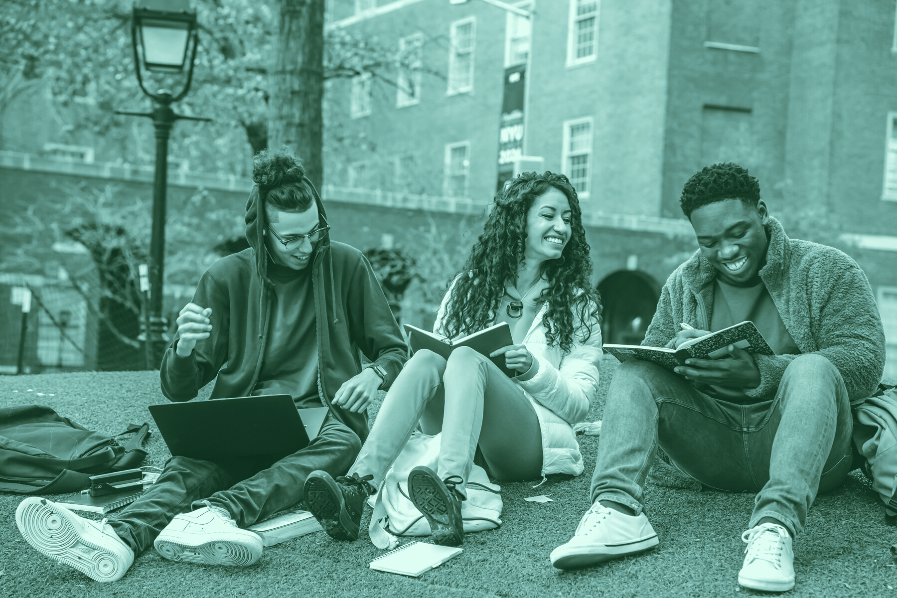Cheerful multiethnic students with books sitting near university